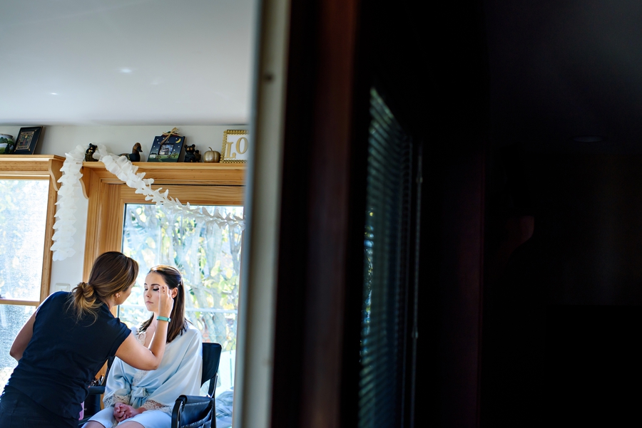 A bride getting her makeup done on her wedding day.